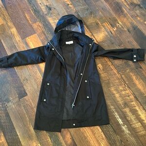 Black rain jacket that zips and placket covers the zipper. Hood w zipper pocket